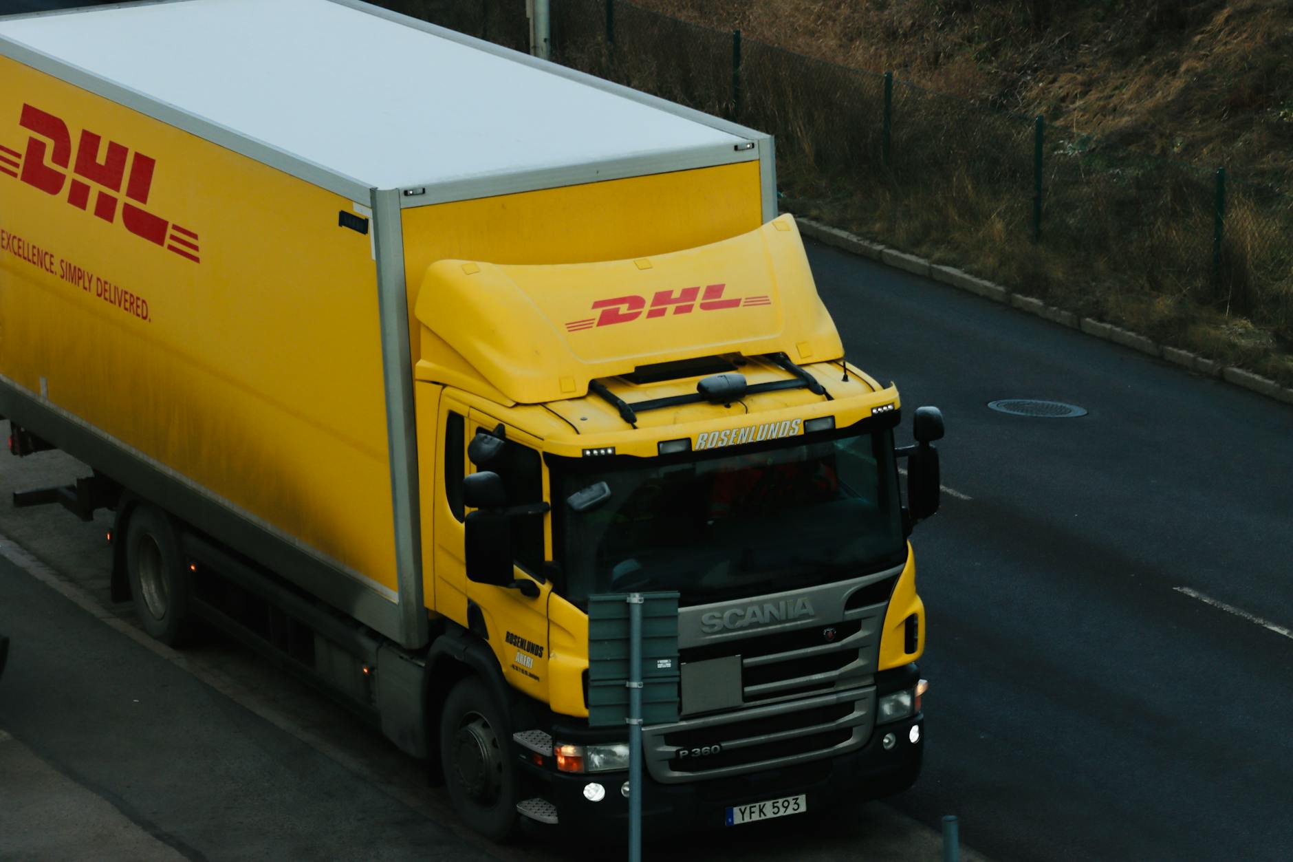 Żółta ciężarówka DHL jedzie ulicą w mieście podczas dostawy