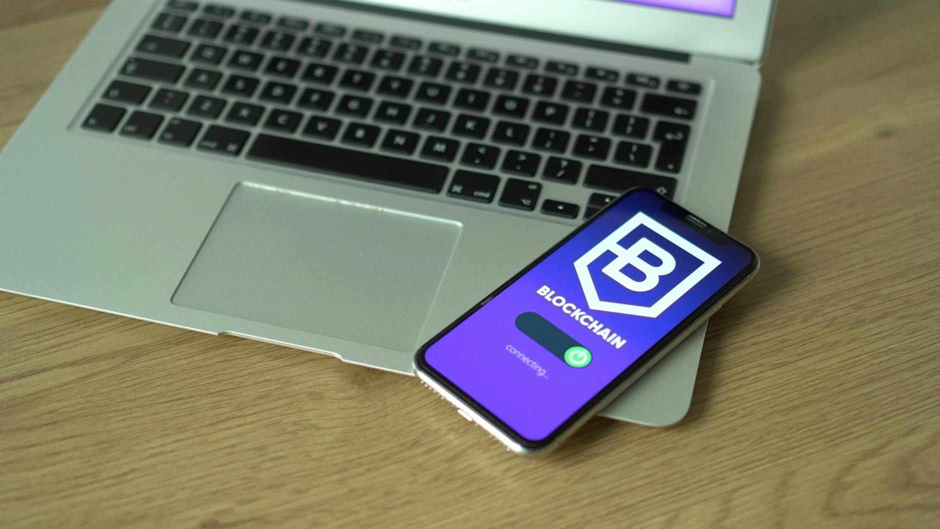 Smartfon z aplikacją finansową na ekranie leżący na klawiaturze laptopa