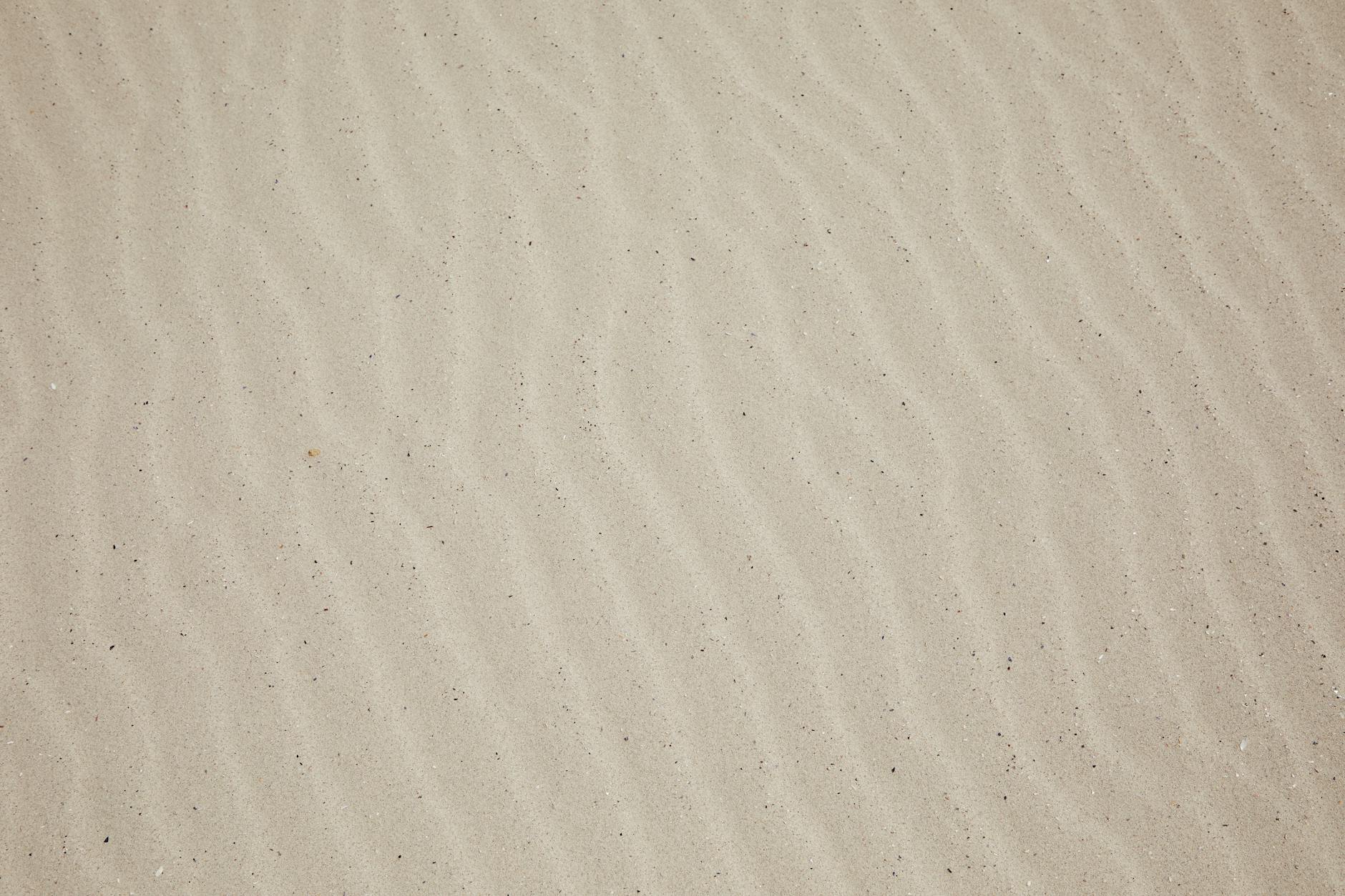 Zbliżenie na równą, jasną powierzchnię piasku na plaży