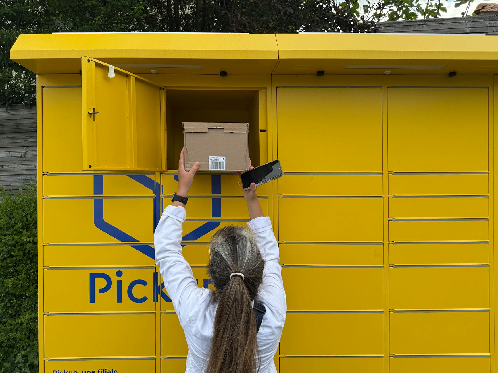 Kobieta próbuje odebrać paczkę z żółtego paczkomatu