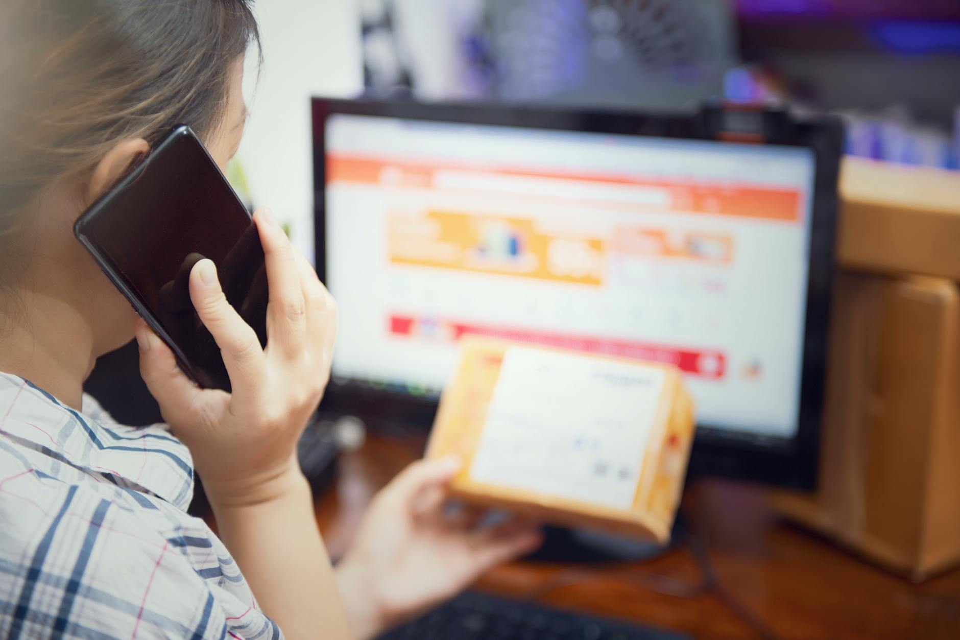 Kobieta w domu sprawdza paczkę pobraniową, trzymając w ręku telefon