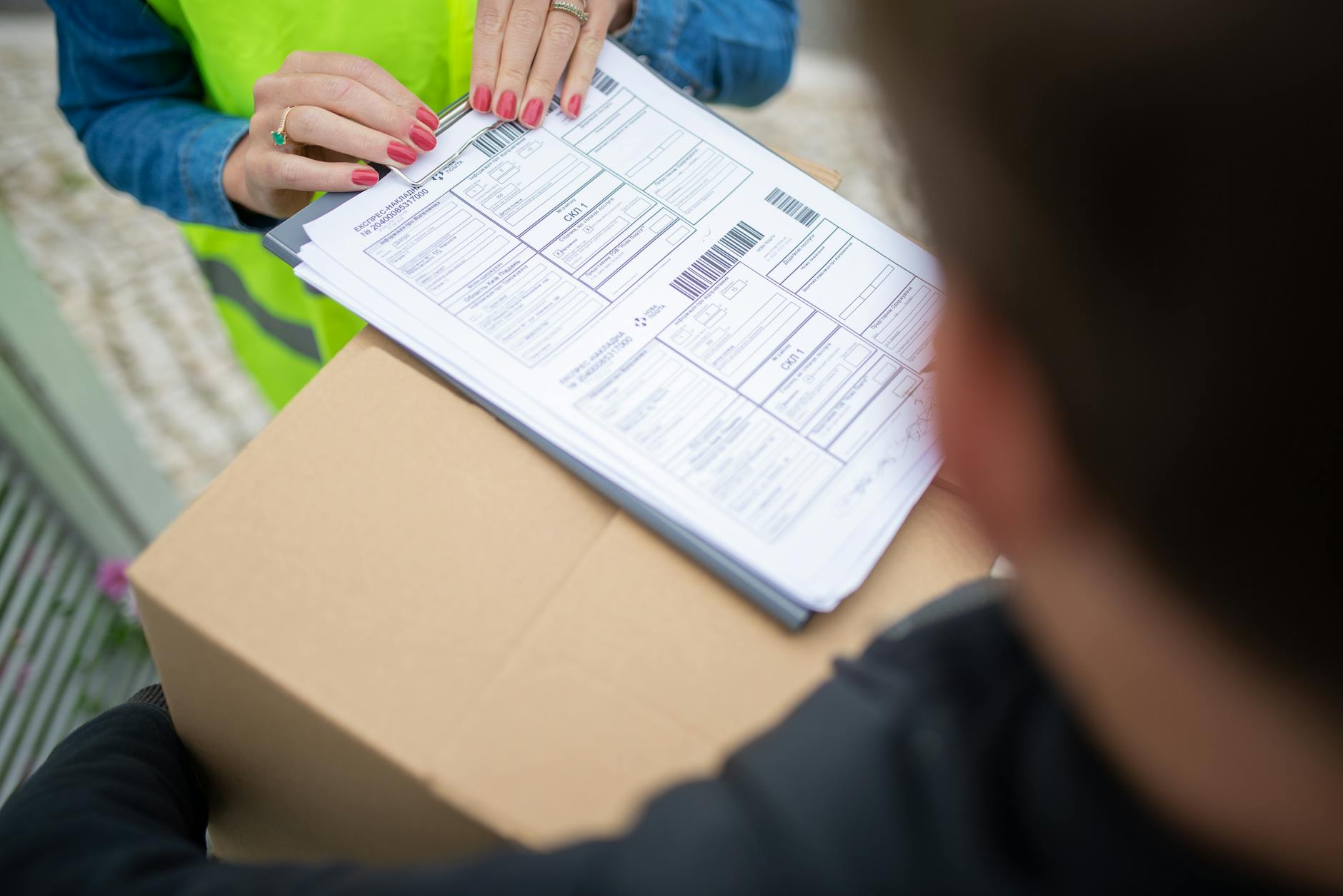Kurier przekazuje paczkę pracownikowi podpisującemu potwierdzenie odbioru