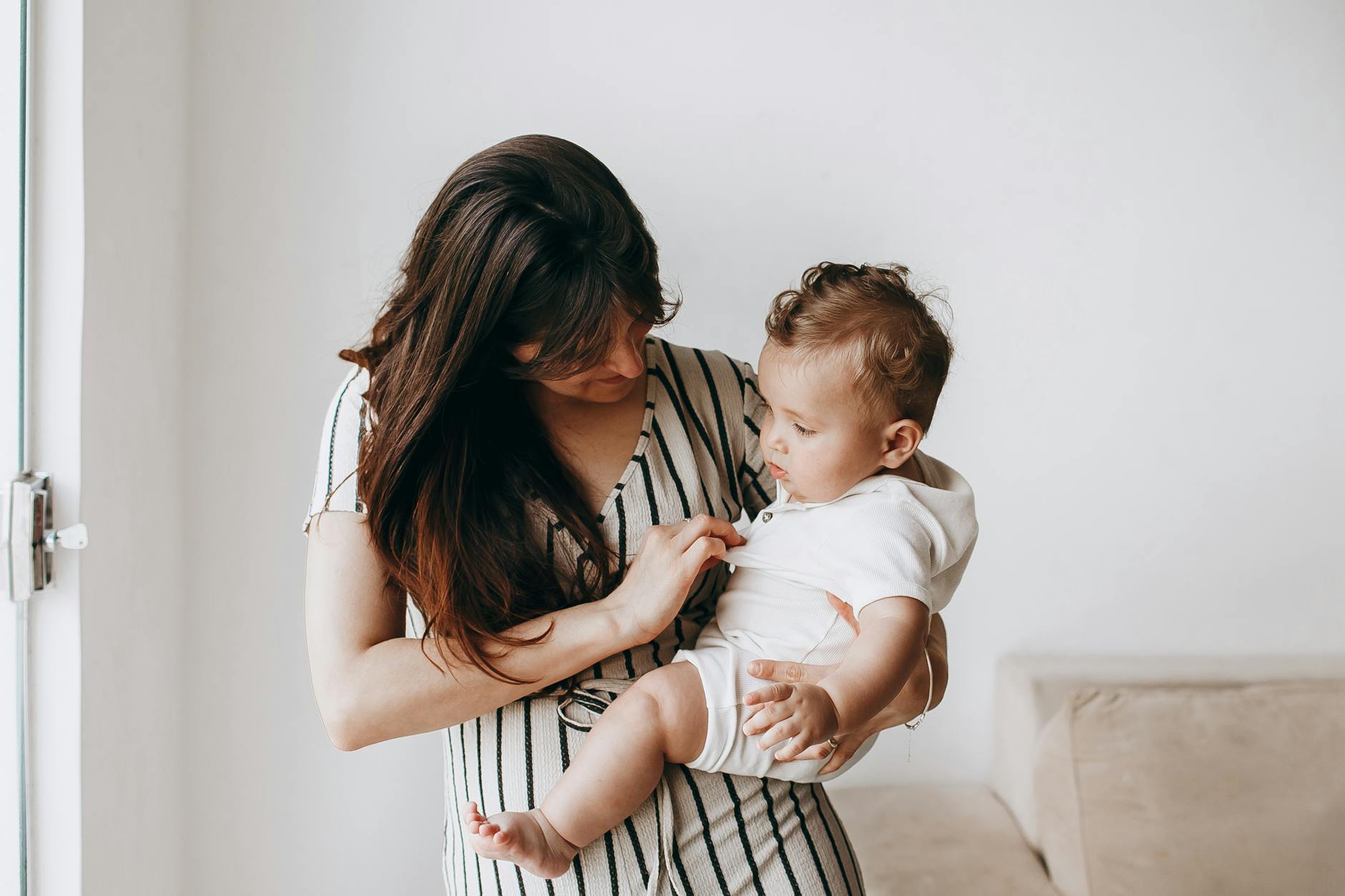 Mama tuląca niemowlę w domu, czuła bliskość i opieka