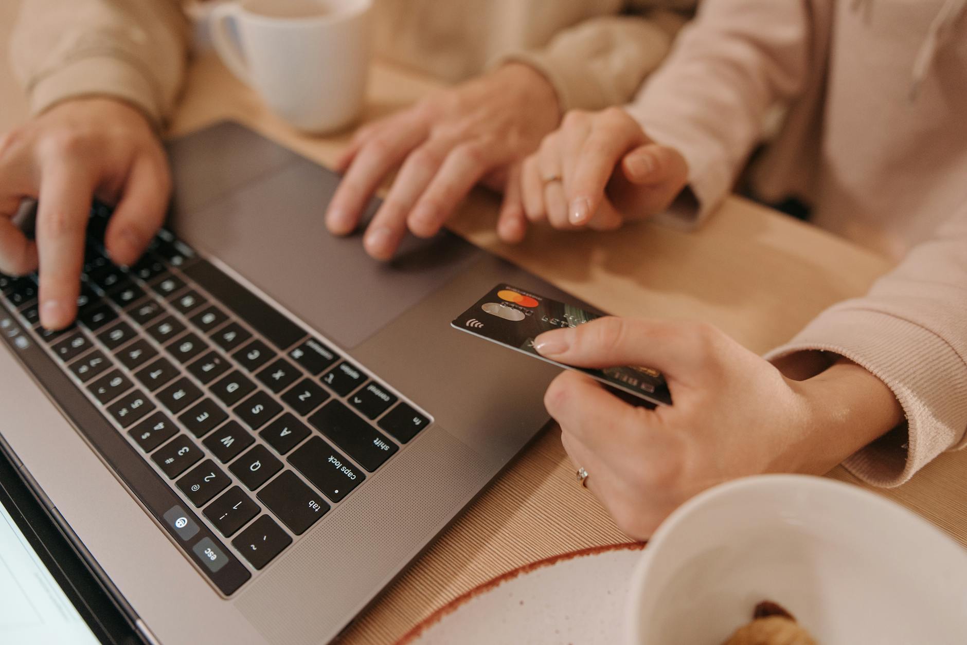 Ręce przy laptopie i karcie kredytowej podczas płatności online