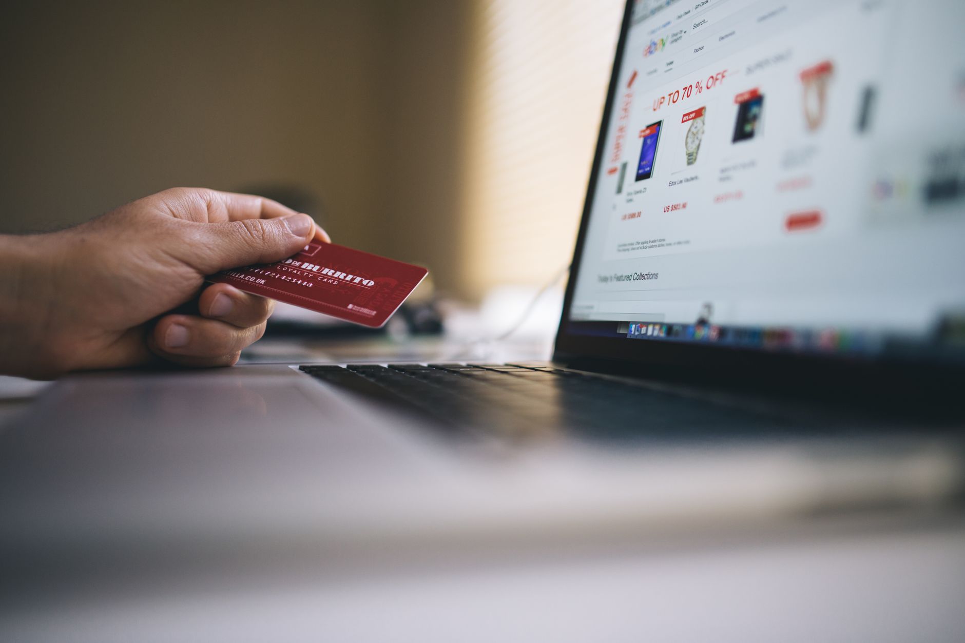 Osoba trzyma kartę kredytową podczas zakupów online na laptopie
